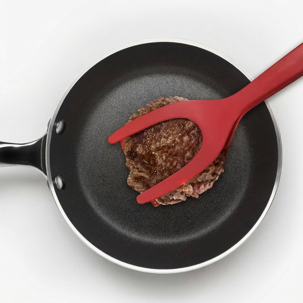 Spatula roșie prinzând un burger într-o tigaie, văzută de sus