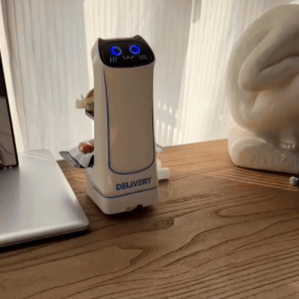 Robot de servire de jucărie pe un birou, cu ochii albaștri luminați